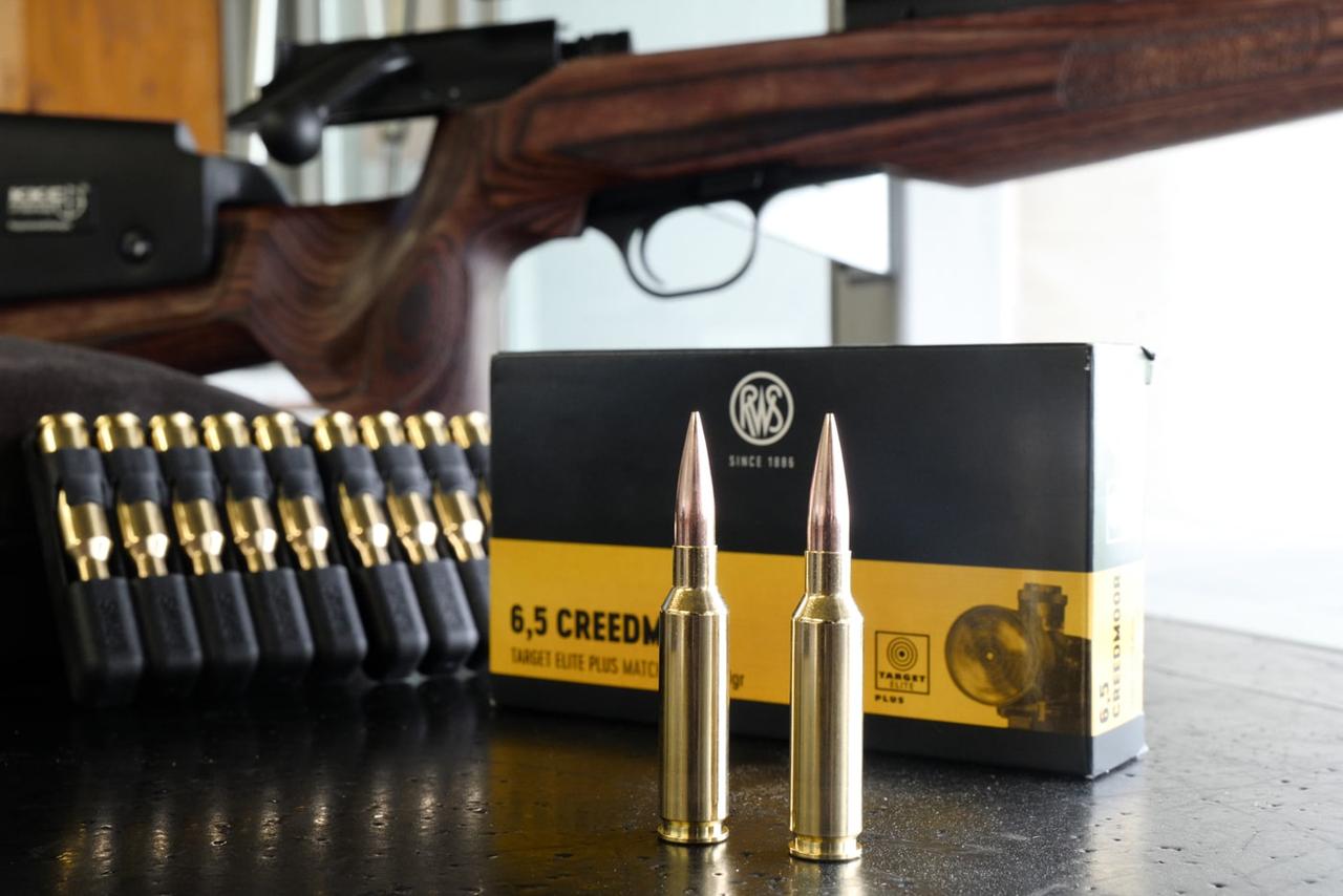 Präsentation der RWS 6,5 Creedmoor Target Elite Plus auf einem Schießstand drapiert neben Verpackung und Gewehr