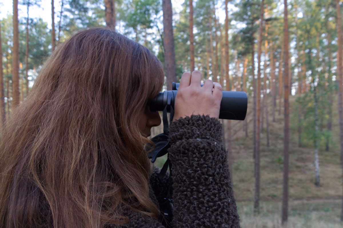 Jägerin im Wald schaut durch ein Fernglas
