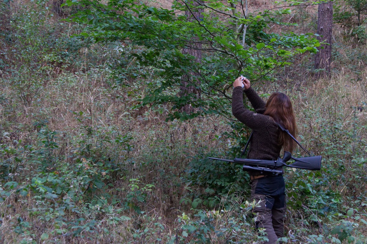 Jägerin mit umgehängten Gewehr im Wald