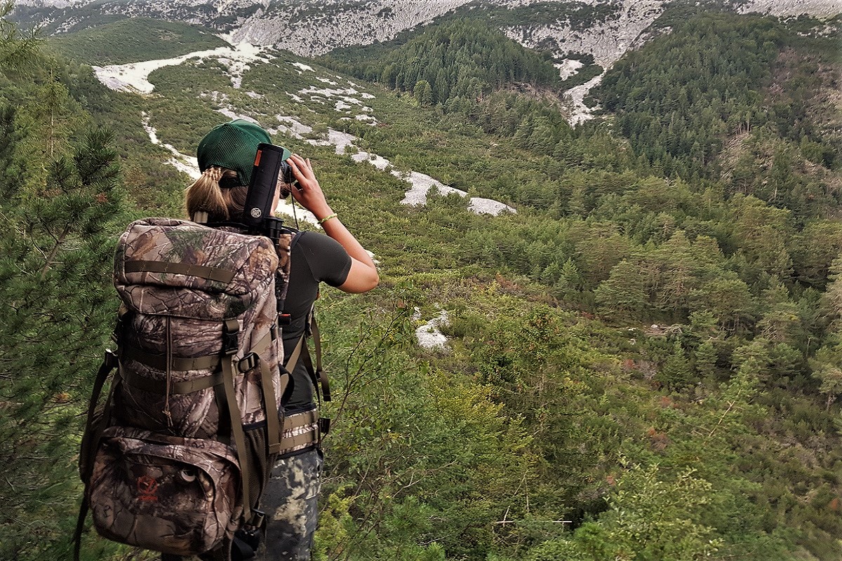Jägerin blickt mit Fernglas über Tiroler Jagdrevier